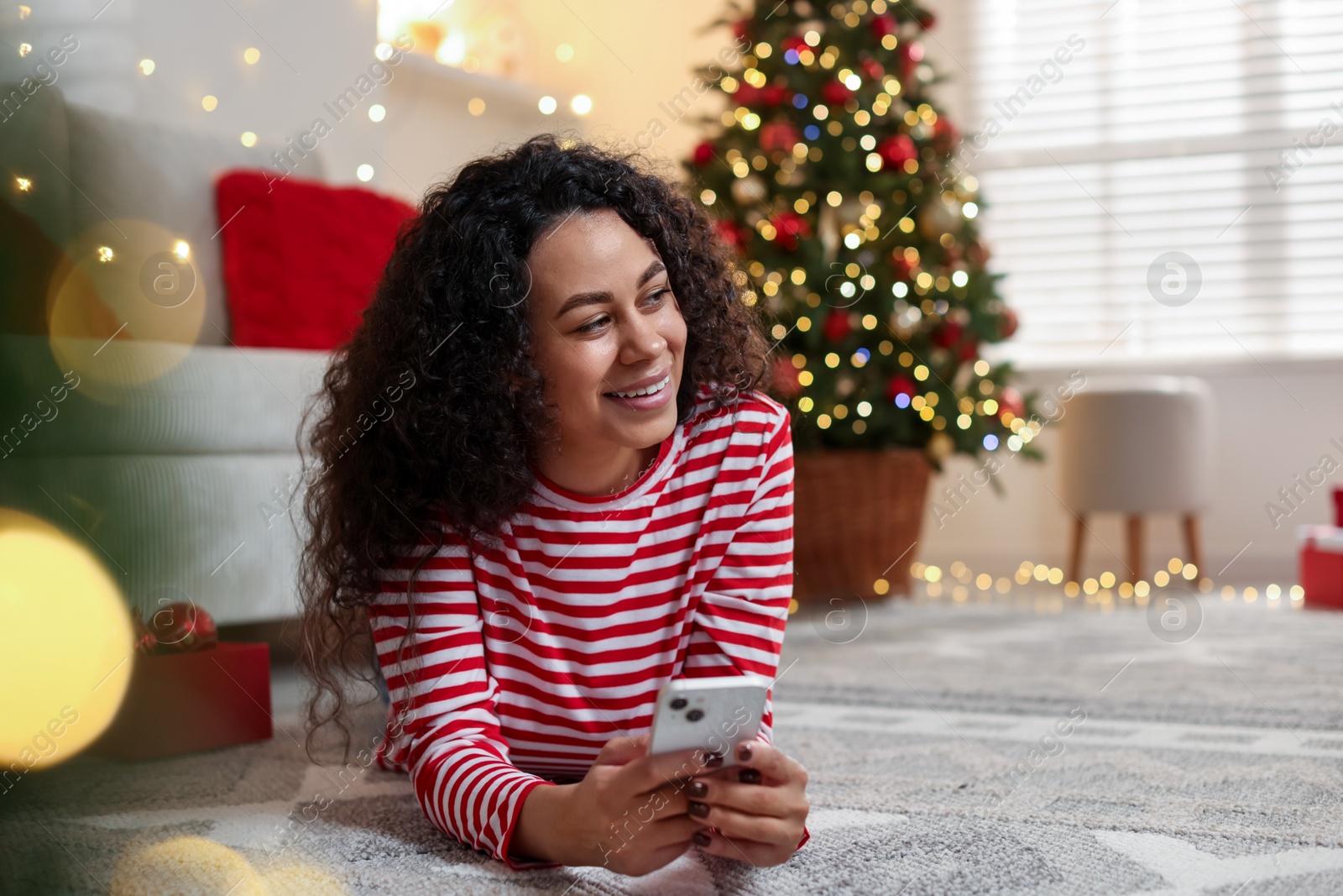 Photo of Happy young woman using smartphone at home. Christmas celebration