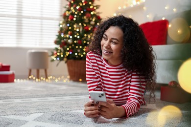 Photo of Happy young woman using smartphone at home. Christmas celebration