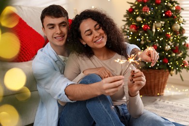 Photo of Happy couple with burning sparklers spending time together at home. Christmas celebration