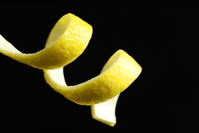 Photo of One curly lemon peel on black background, closeup