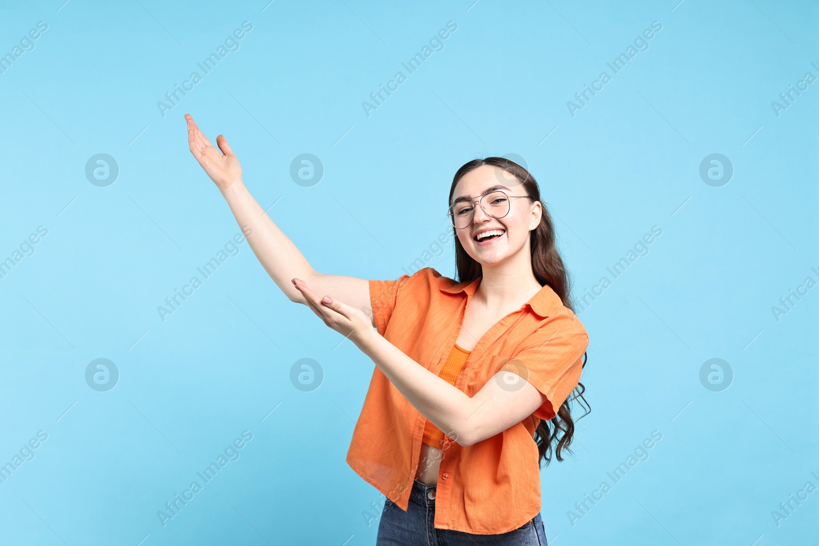 Photo of Happy woman welcoming friends or guests on light blue background