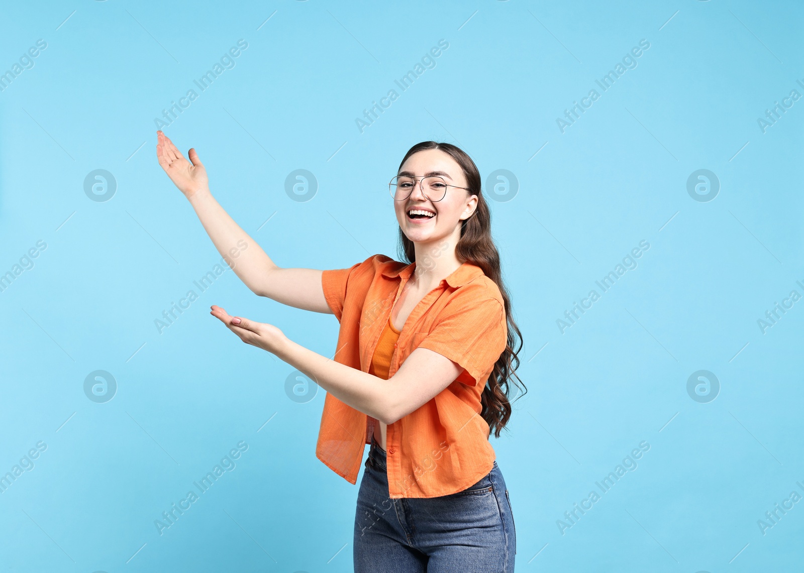 Photo of Happy woman welcoming friends or guests on light blue background