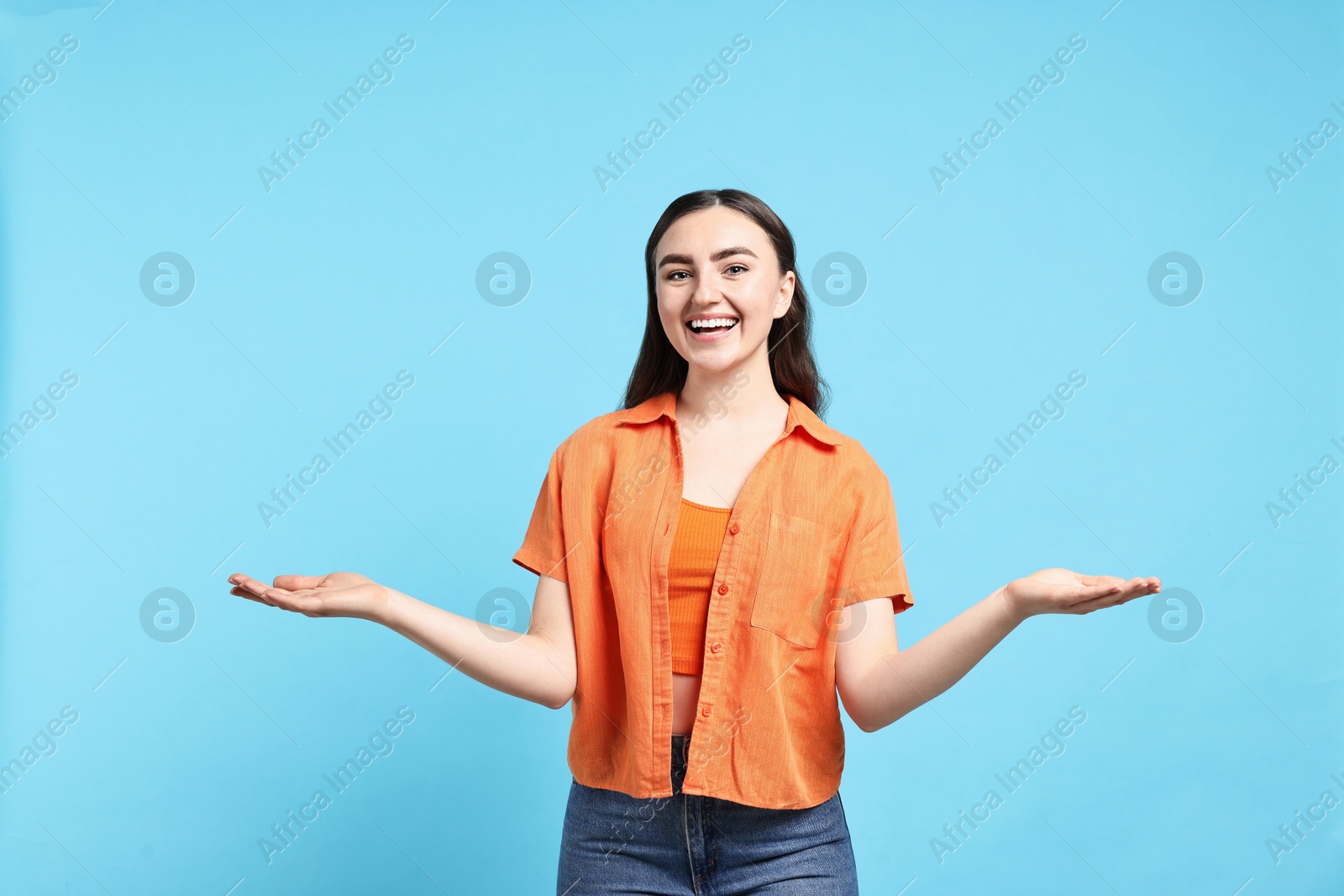 Photo of Happy woman welcoming friends or guests on light blue background