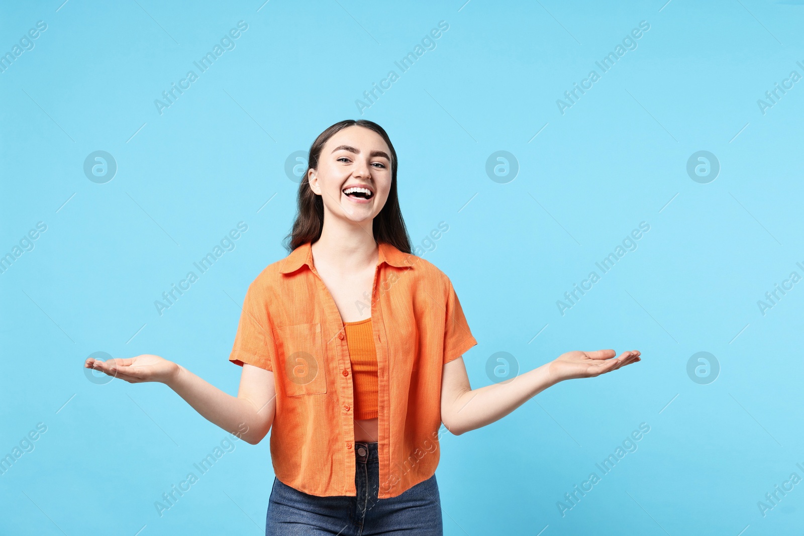 Photo of Happy woman welcoming friends or guests on light blue background