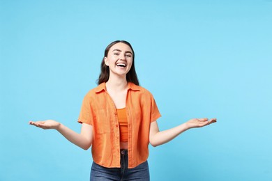 Photo of Happy woman welcoming friends or guests on light blue background