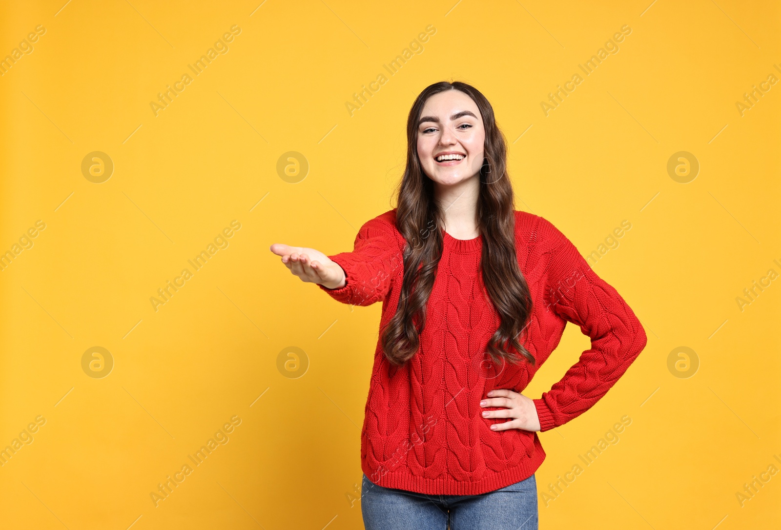 Photo of Happy woman welcoming friends or guests on yellow background