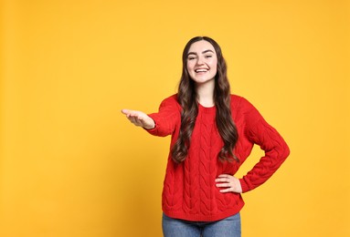 Photo of Happy woman welcoming friends or guests on yellow background