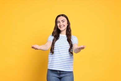 Photo of Happy woman welcoming friends or guests on yellow background