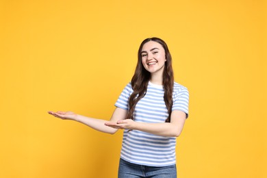 Photo of Happy woman welcoming friends or guests on yellow background