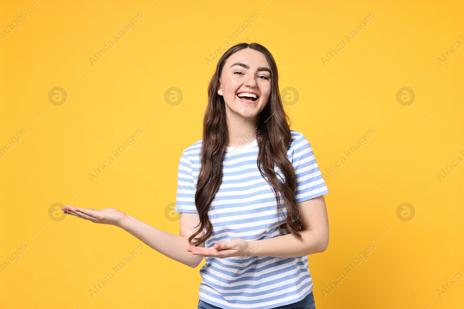 Photo of Happy woman welcoming friends or guests on yellow background