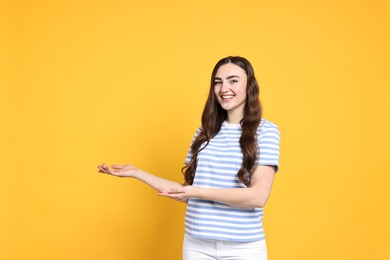 Photo of Happy woman welcoming friends or guests on yellow background