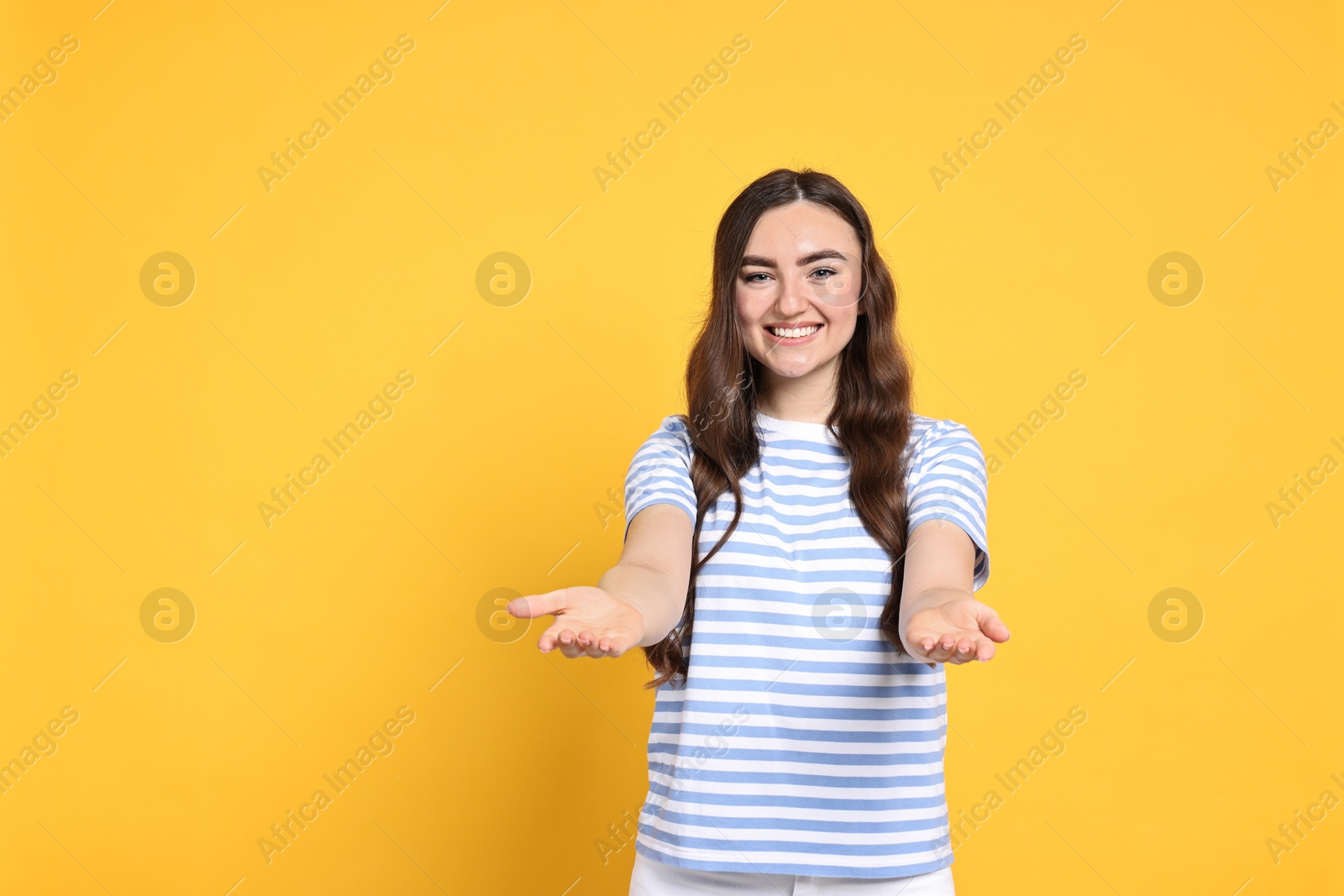 Photo of Happy woman welcoming friends or guests on yellow background