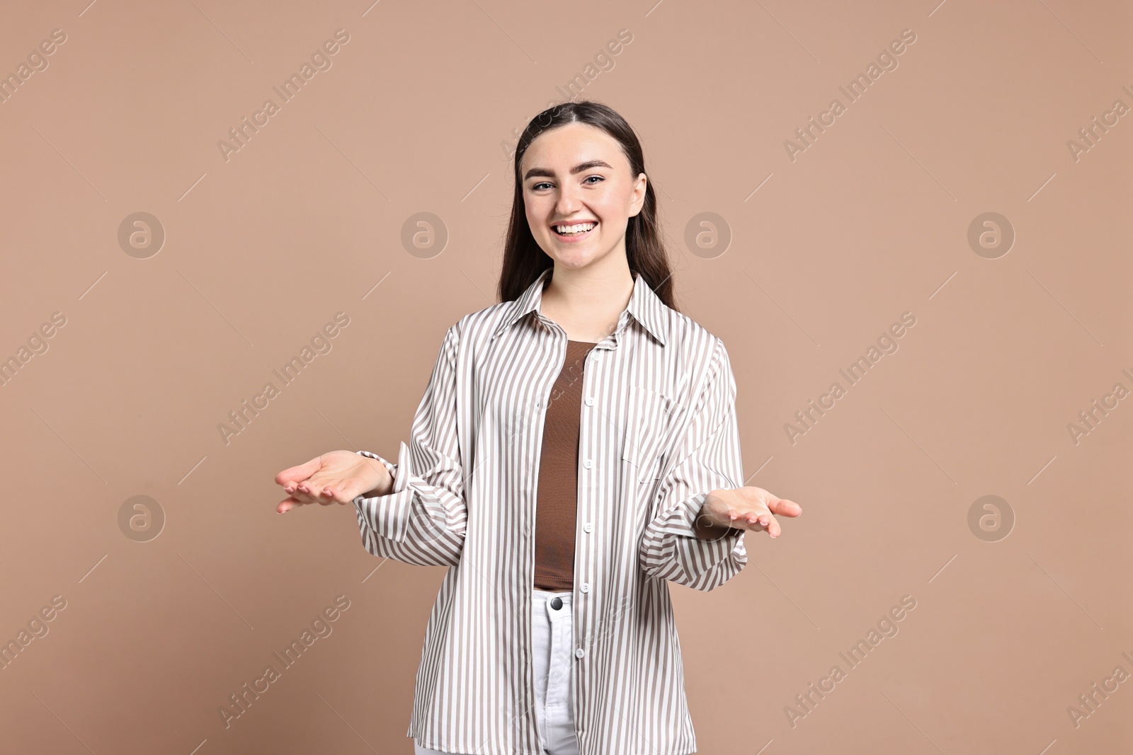 Photo of Happy woman welcoming friends or guests on beige background