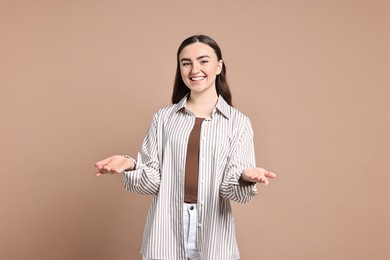 Photo of Happy woman welcoming friends or guests on beige background