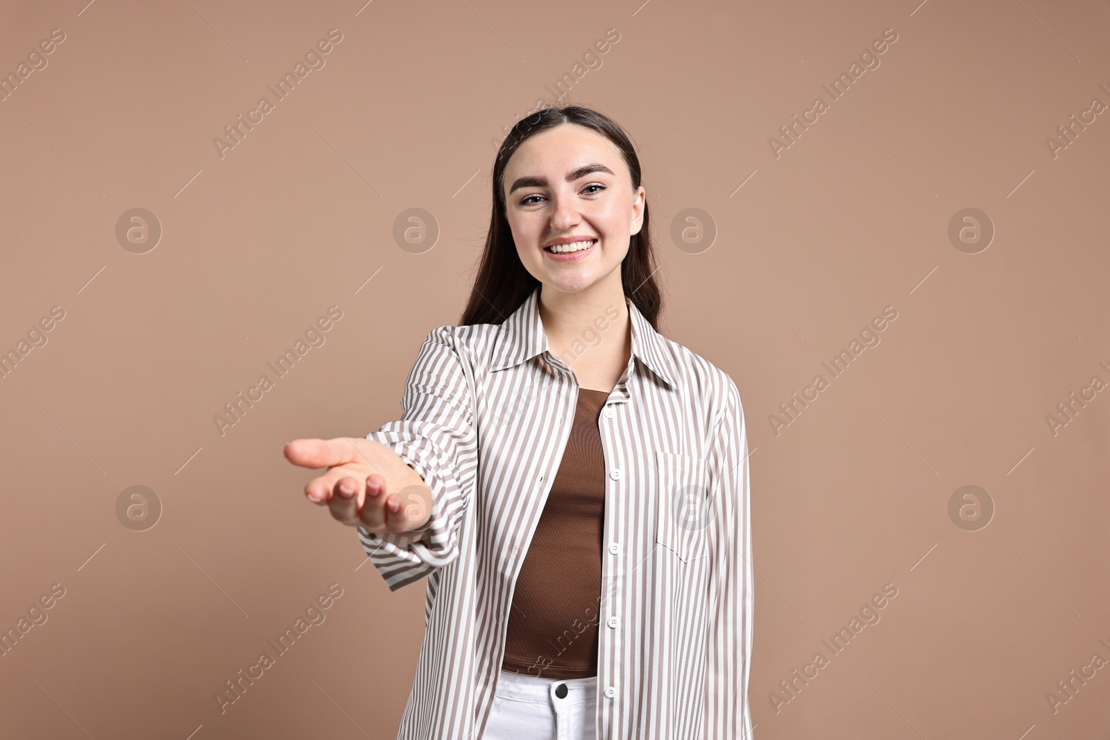 Photo of Happy woman welcoming friends or guests on beige background