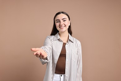 Photo of Happy woman welcoming friends or guests on beige background