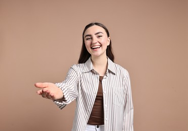 Photo of Happy woman welcoming friends or guests on beige background