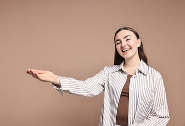 Photo of Happy woman welcoming friends or guests on beige background