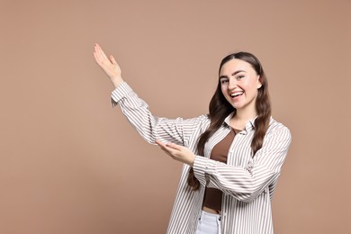 Photo of Happy woman welcoming friends or guests on beige background. Space for text