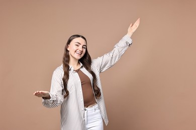 Photo of Happy woman welcoming friends or guests on beige background. Space for text