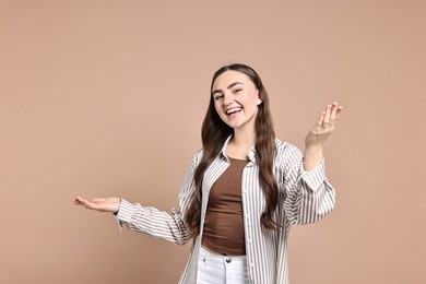 Photo of Happy woman welcoming friends or guests on beige background. Space for text