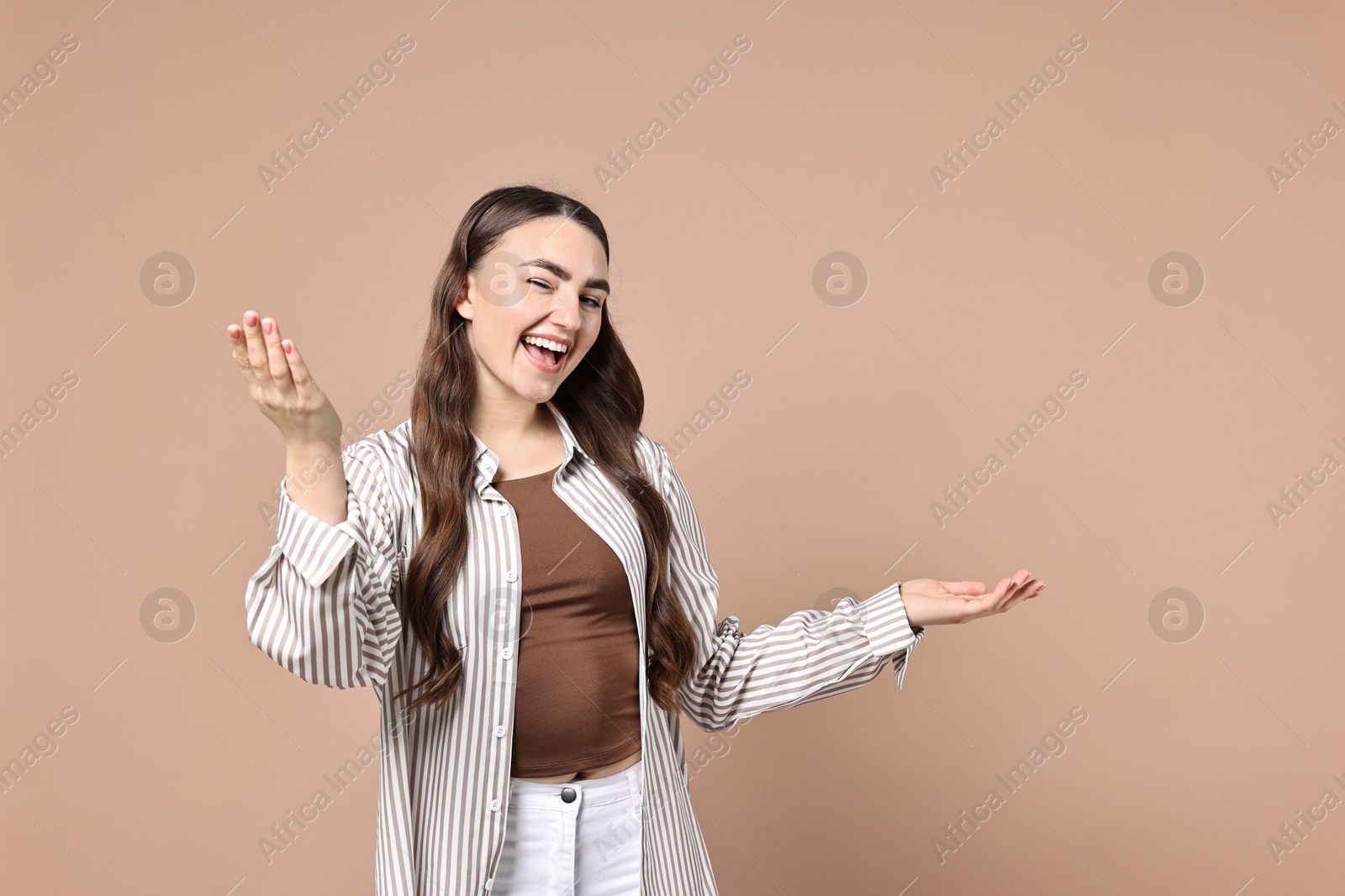 Photo of Happy woman welcoming friends or guests on beige background. Space for text