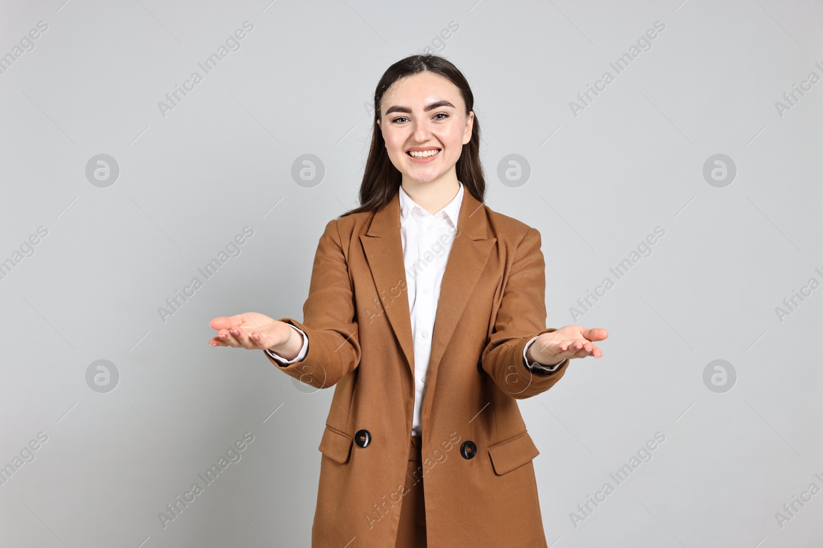 Photo of Happy businesswoman welcoming clients or partners on grey background