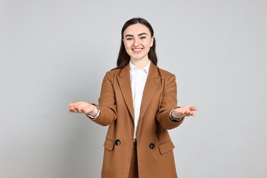 Photo of Happy businesswoman welcoming clients or partners on grey background