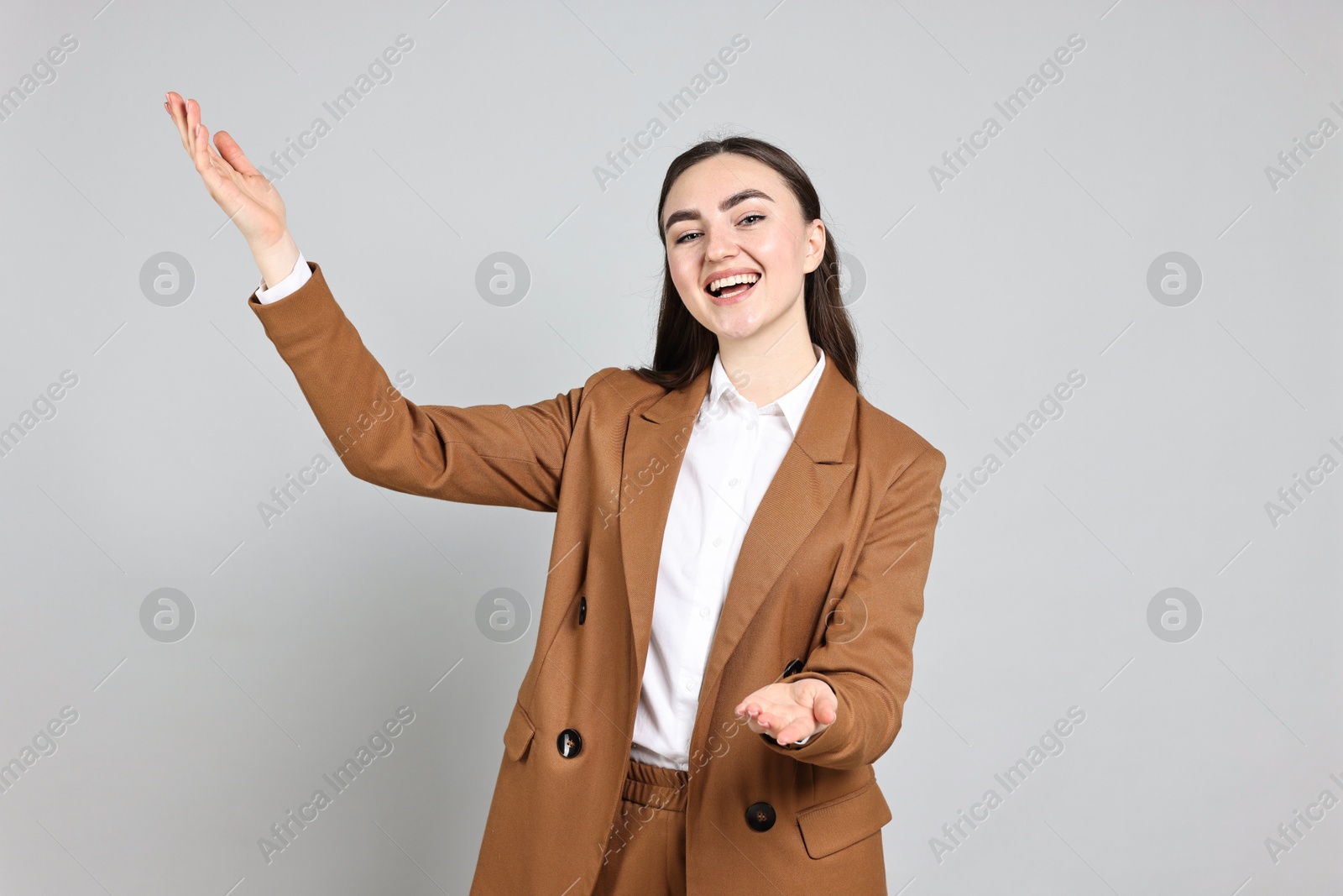 Photo of Happy businesswoman welcoming clients or partners on grey background