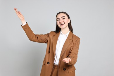 Photo of Happy businesswoman welcoming clients or partners on grey background