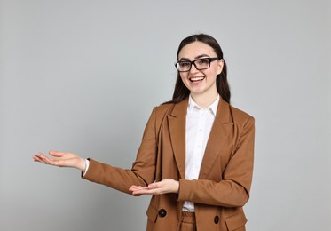 Photo of Happy businesswoman welcoming clients or partners on grey background