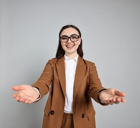 Photo of Happy businesswoman welcoming clients or partners on grey background