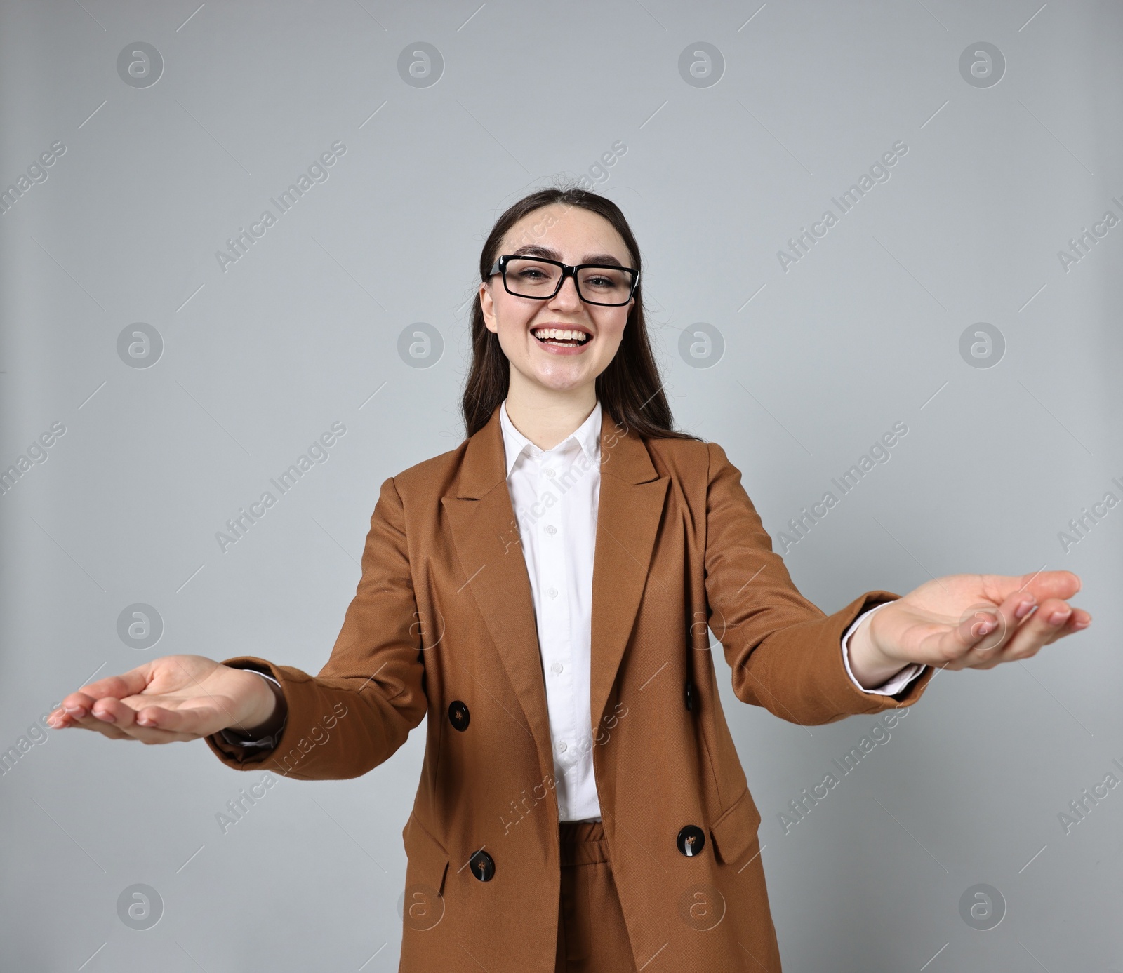 Photo of Happy businesswoman welcoming clients or partners on grey background