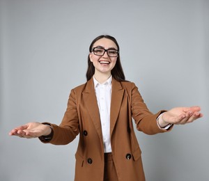 Photo of Happy businesswoman welcoming clients or partners on grey background