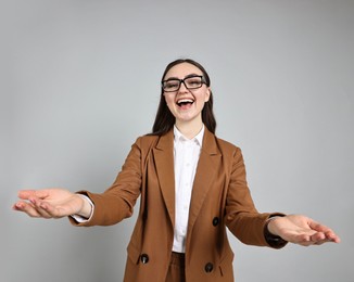 Photo of Happy businesswoman welcoming clients or partners on grey background