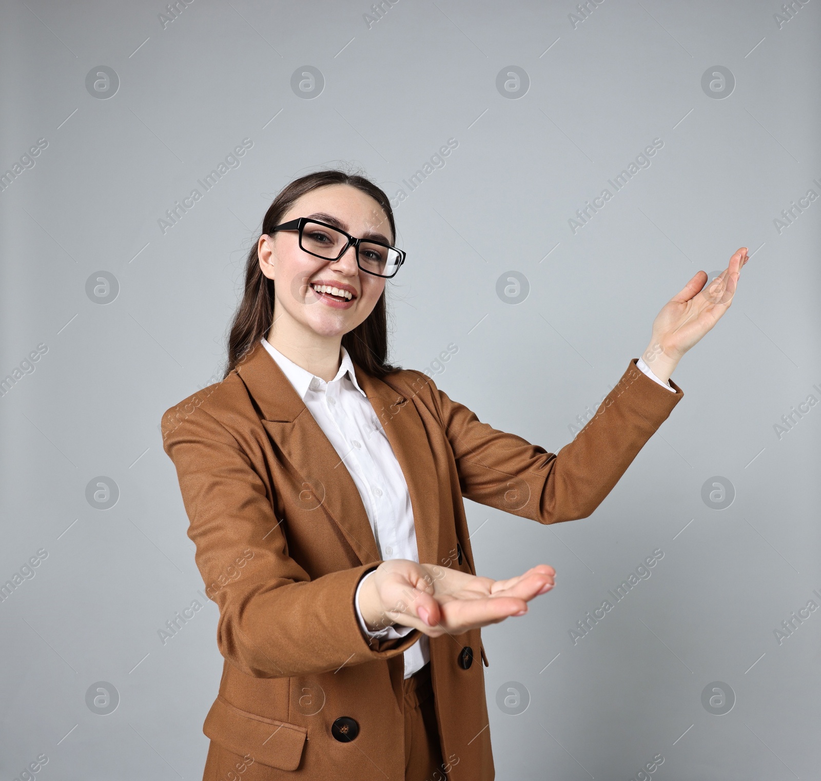 Photo of Happy businesswoman welcoming clients or partners on grey background