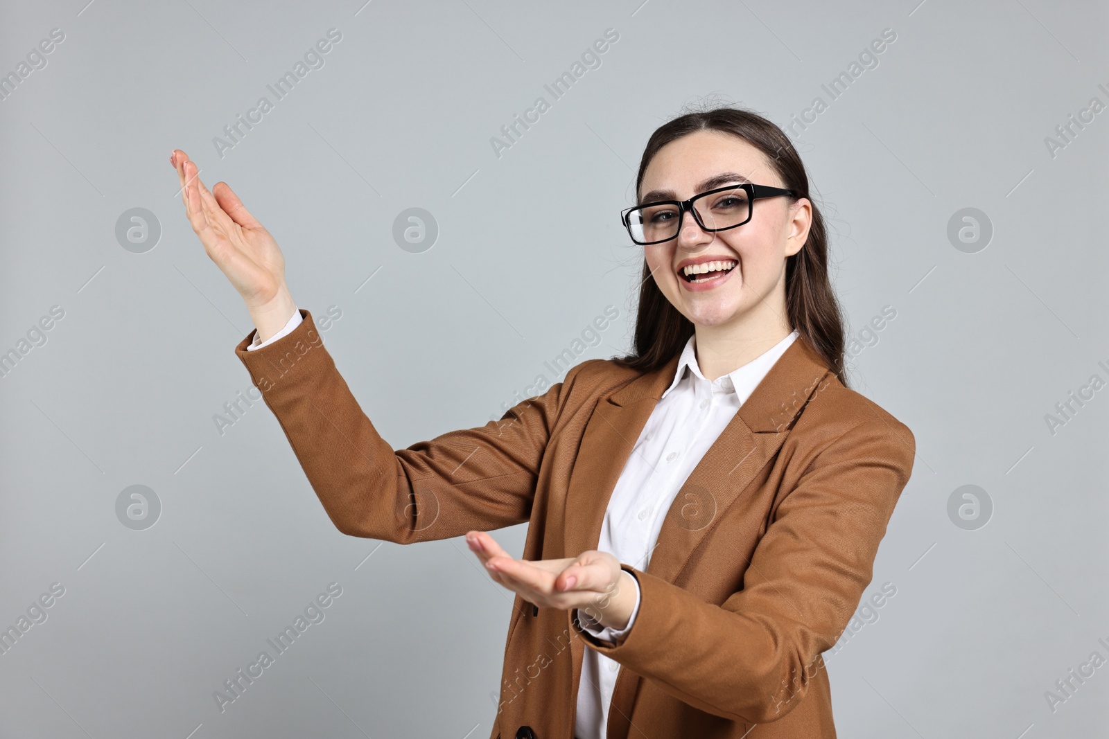 Photo of Happy businesswoman welcoming clients or partners on grey background