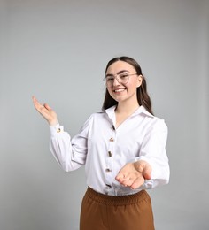 Photo of Happy businesswoman welcoming clients or partners on grey background. Space for text