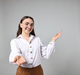 Photo of Happy businesswoman welcoming clients or partners on grey background. Space for text