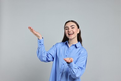 Photo of Happy woman welcoming somebody on grey background