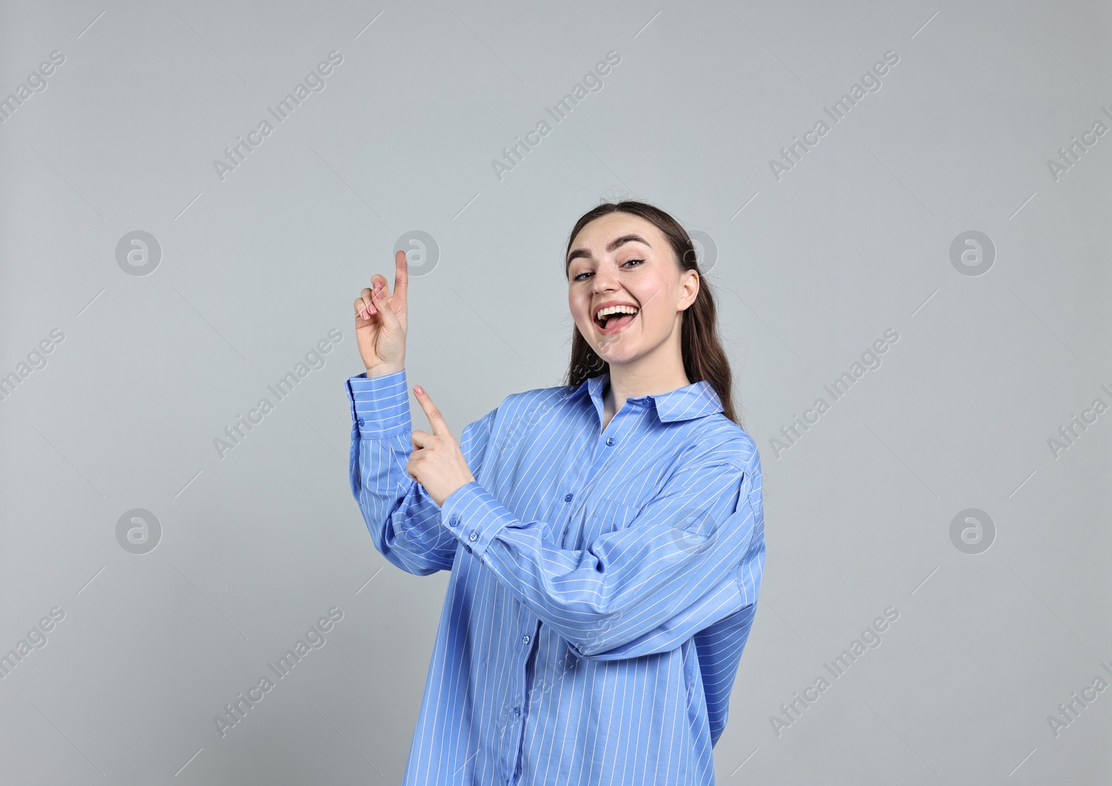 Photo of Happy woman welcoming somebody on grey background