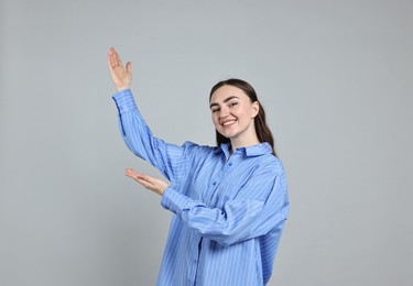 Photo of Happy woman welcoming somebody on grey background