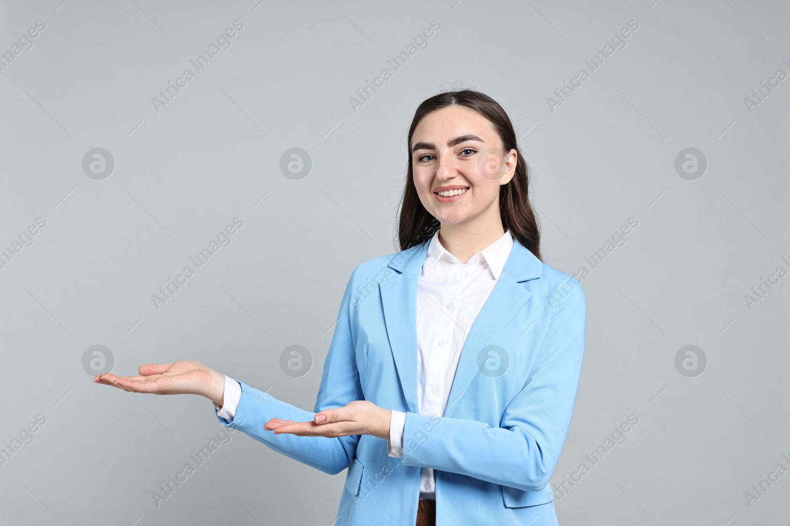 Photo of Happy businesswoman welcoming clients or partners on grey background