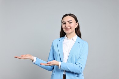 Photo of Happy businesswoman welcoming clients or partners on grey background