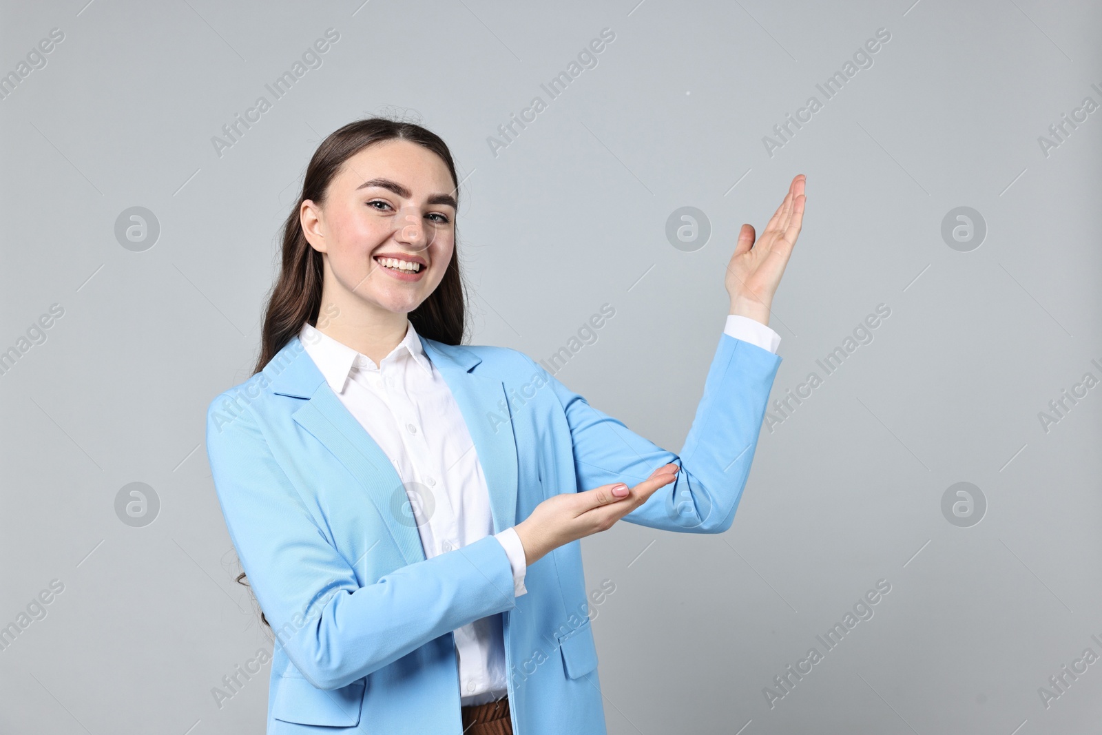 Photo of Happy businesswoman welcoming clients or partners on grey background