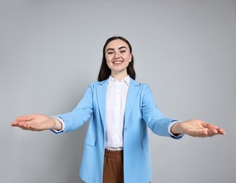 Photo of Happy businesswoman welcoming clients or partners on grey background