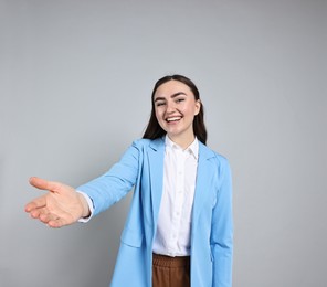 Photo of Happy businesswoman welcoming clients or partners on grey background