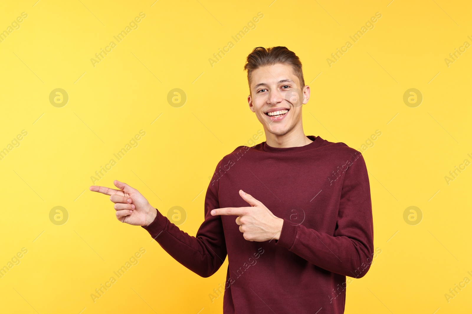 Photo of Happy man welcoming friends or guests on yellow background