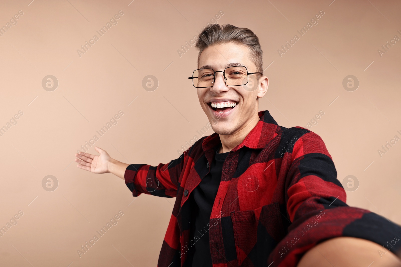 Photo of Happy man taking selfie and welcoming friends or guests on beige background. Space for text