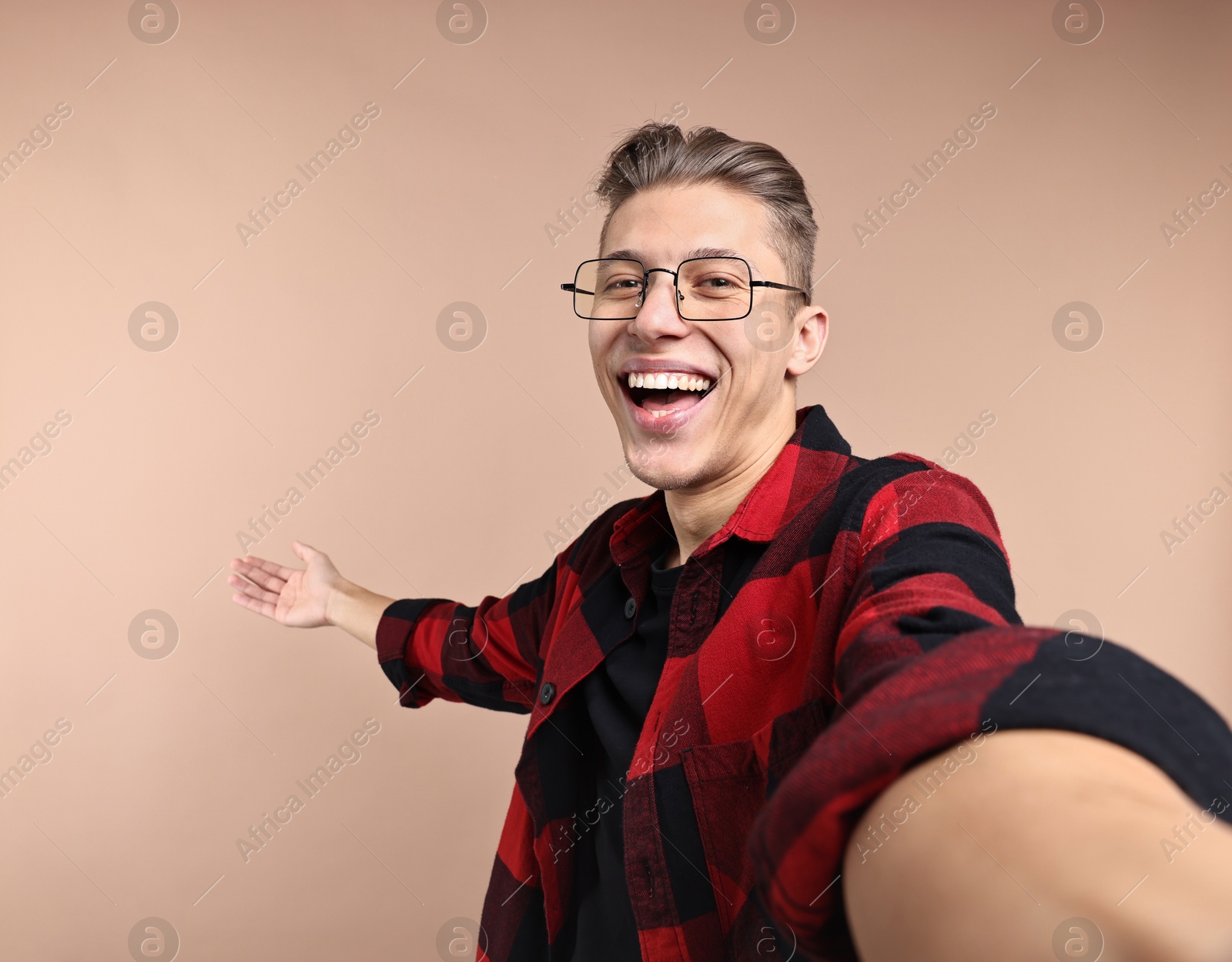 Photo of Happy man taking selfie and welcoming friends or guests on beige background. Space for text